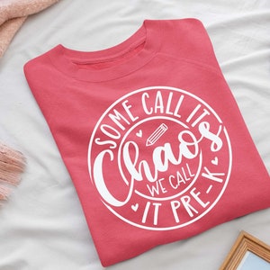 May include: A pink sweatshirt with a white circle design that says "Some call it chaos we call it pre-k" with a pencil and hearts inside the circle.