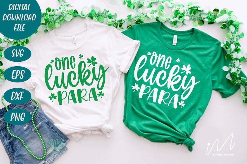 May include: Two white t-shirts with green shamrock designs. The text on the shirts reads "one lucky *PARA*" in green lettering. The shirts are laid out on a white surface with green garland.