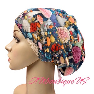 May include: A colorful surgical scrub hat with a mushroom and flower pattern. The hat has a tie at the back.