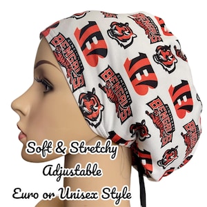 May include: A white and red Cincinnati Bengals print scrub cap. The cap features the team's logo and name. The cap is soft, stretchy, and adjustable. The text on the cap says "Soft & Stretchy, Adjustable, Euro or Unisex Style."