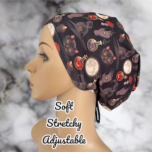 May include: Black and white patterned surgical scrub hat with a design of cats, moons, and potion bottles. The hat is soft, stretchy, and adjustable.