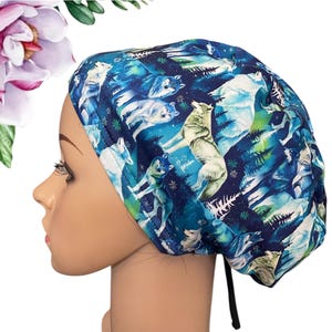 May include: A blue and white patterned scrub cap featuring a wolf and forest design. The cap is made of a soft fabric and has a black drawstring. The cap is designed to be worn during medical procedures.