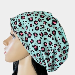 May include: A turquoise blue and pink leopard print satin sleep cap. The cap is made of soft, stretchy fabric and is designed to protect hair from breakage and frizz.