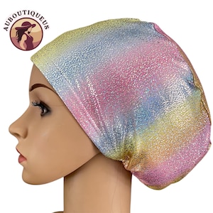 May include: A colorful head covering with a textured, iridescent finish. The fabric transitions through shades of yellow, pink, blue, and gold. The head covering is worn by a mannequin. The logo "AUBOUTIQUEUS" is in the upper left corner.