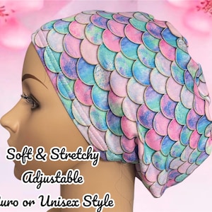May include: A scrub cap featuring a repeating pattern of iridescent mermaid scales in shades of pink, blue, and purple. The fabric has a soft, stretchy texture. Text on the image reads: Soft & Stretchy, Adjustable, Euro or Unisex Style.