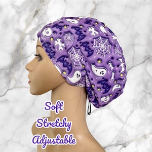 May include: Purple and white shower cap with a Halloween theme featuring ghosts, bats, and spiderwebs. The cap is soft, stretchy, and adjustable.