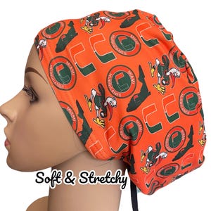 May include: Orange and green surgical scrub hat with a repeating pattern of the University of Miami Hurricanes logo and mascot. The text "Miami Hurricanes" is visible on the hat.