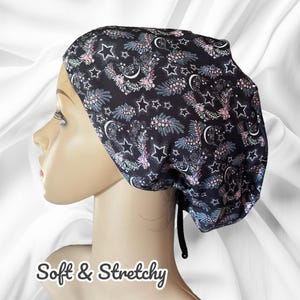 May include: A black scrub hat with a pink and blue star and crescent moon pattern. The hat is soft and stretchy and has a tie at the back.