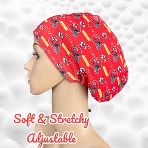 May include: Red and yellow adjustable scrub hat with a pattern of football helmets. The hat is soft and stretchy. "Soft & Stretchy Adjustable" is written in red text below the hat.