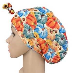 May include: A colorful scrub cap featuring a pattern of orange, blue, and green pumpkins with yellow sunflowers. The cap is designed to fit comfortably and is made of a soft, breathable fabric. The cap is a fall-themed accessory.