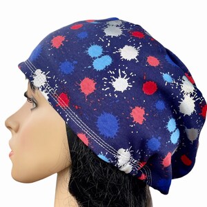 May include: A blue beanie with a white, red, and blue paint splatter pattern.