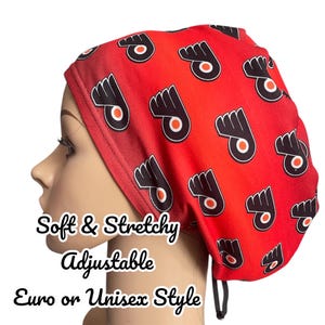 May include: Red and black adjustable scrub hat with a repeating pattern of a hockey team logo. The hat is soft and stretchy.  The text "Soft & Stretchy Adjustable Euro or Unisex Style" is printed below the hat.