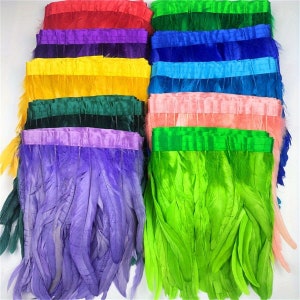 May include: Assortment of colourful feather trim with a variety of colours including red, purple, yellow, green, blue, and pink. The feather trim is arranged in rows and is ready to be used for crafting projects.