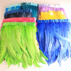 May include: Assortment of feather trim in various colours, including green, blue, yellow, pink, and teal. Each trim features a satin ribbon edge.