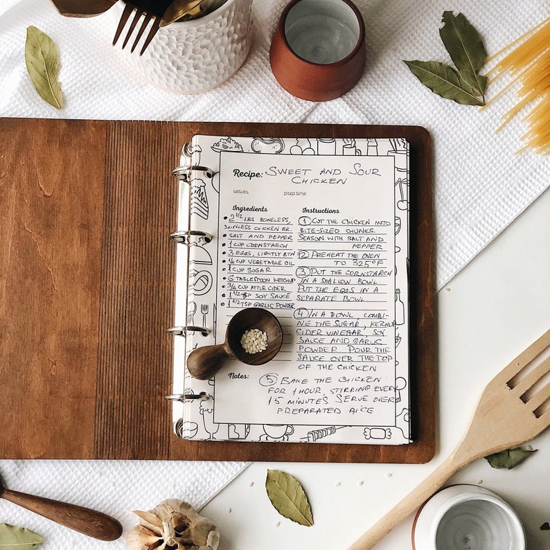 Puede incluir: Una receta de Pollo Agridulce escrita en tinta negra en una p&aacute;gina blanca de un libro de recetas encuadernado. La receta incluye ingredientes como pollo sin hueso ni piel, sal, pimienta, maicena, huevos, aceite vegetal, az&uacute;car, vinagre de sidra de manzana, salsa de soja y ajo en polvo. Las instrucciones incluyen cortar el pollo en trozos del tama&ntilde;o de un bocado, precalentar el horno a 160 grados Celsius y hornear el pollo durante cuatro horas, revolviendo cada 15 minutos.
