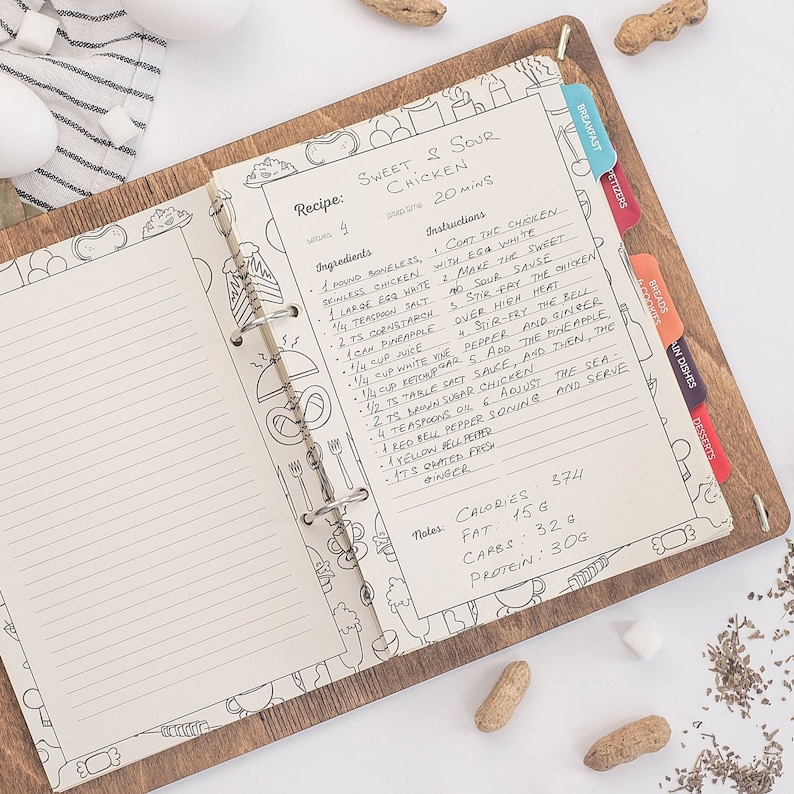 May include: A recipe for Sweet & Sour Chicken, written in a recipe book with a brown wooden cover. The recipe includes ingredients like boneless chicken, egg white, pineapple, and bell peppers. The recipe also includes nutritional information for calories, fat, carbs, and protein.