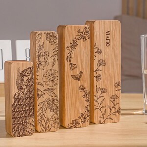 May include: Four wooden boxes with engraved floral designs and the name "Olivia" on one box. The boxes are arranged in a row from left to right, with the largest box on the right and the smallest box on the left.