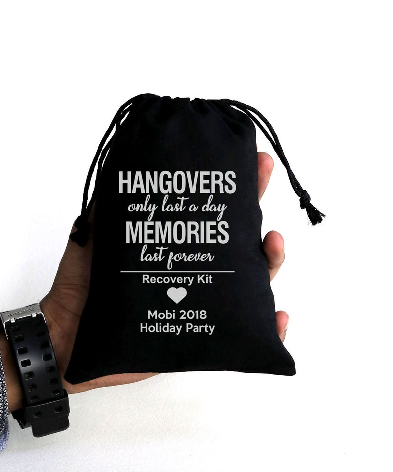 May include: A black drawstring bag with white text that reads "Hangovers only last a day, memories last forever." Below the text is "Recovery Kit" and "Mobi 2018 Holiday Party."