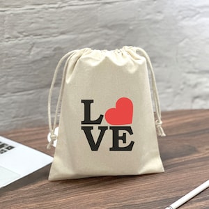 May include: A white drawstring bag with the word "LOVE" printed in black with a red heart in the middle of the "O".