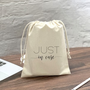May include: A white drawstring bag with the text "JUST in case" printed in black.