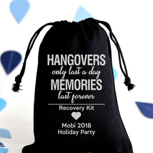 May include: Black drawstring bag with white text: "Hangovers only last a day, memories last forever." Below, it reads "Recovery Kit" and "Mobi 2018 Holiday Party." A white heart graphic is also present. The bag is on a white background.