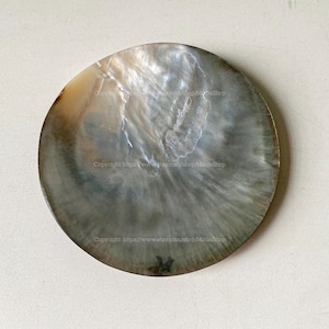 May include: A round, iridescent mother-of-pearl shell with a pearlescent sheen. The shell has a natural, organic shape and a smooth, polished surface. The colors range from white to gray and brown.