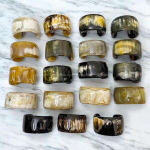 May include: A collection of 18 horn bracelets in various colors and patterns. The bracelets are made of natural horn and have a polished finish. They are all different sizes and shapes, but they are all beautiful and unique.