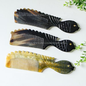 May include: Three fish-shaped combs made of horn. The combs are black, brown, and yellow. The combs have a fine-toothed design.