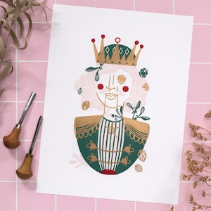 May include: A gold crown with red accents sits atop a green and gold illustration of a nutcracker. The nutcracker is surrounded by floral and leaf motifs.