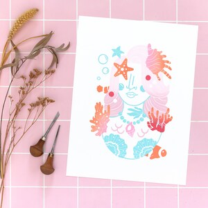 May include: A colorful illustration of a mermaid with pink hair, surrounded by seashells, coral, and a starfish. The mermaid is wearing a necklace with a seashell pendant.