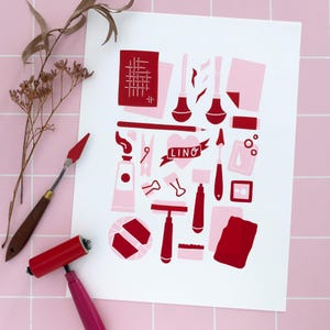May include: A linocut art print with red and pink tools, including a roller and palette knife. The word "LINO" is on a banner. The print is on a white background, with a pink tile surface.