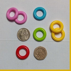 May include: Assortment of colorful plastic rings, some stacked on top of each other. The rings are in various colors, including pink, blue, green, and yellow.