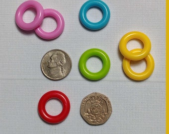 May include: Assortment of colorful plastic rings, some stacked on top of each other. The rings are in various colors, including pink, blue, green, and yellow.
