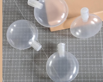Op de afbeelding: Vier transparante plastic hondenspeelgoed met een pieper erin. De speelgoedjes zijn rond met een klein handvat aan de bovenkant.