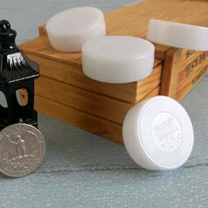 May include: Four white round plastic containers with a black and white label on one of the containers that reads "ITEM NO. 803 SIZE: 8333112 ASTN: 15803 CE"