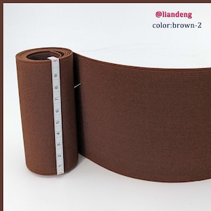 May include: A roll of brown elastic fabric with a measuring tape next to it. The elastic is 9 inches wide.