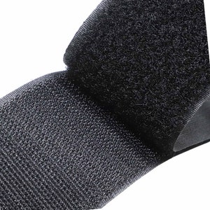 May include: Close-up of black hook and loop fastener material. The image shows the textured surface of the hook and loop, with the loops and hooks clearly visible. The material is a solid black colour.