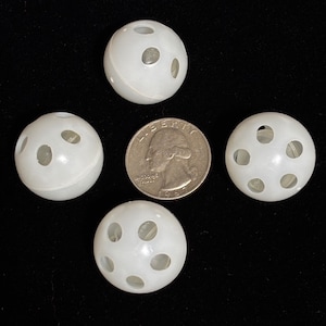 May include: Four small, spherical, white plastic balls with multiple circular cutouts arranged around their surface. A United States quarter coin is positioned in the center for scale, showing the balls are approximately 0.95 inches in diameter.