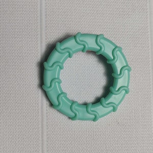May include: A turquoise blue plastic ring with a wavy design. The ring is about 2 inches in diameter.