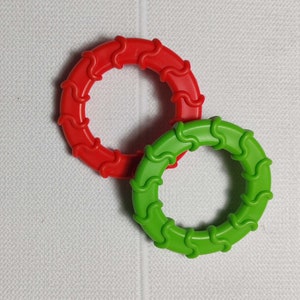 May include: Two plastic rings, one red and one green, with a wavy design. The rings are interlocked.