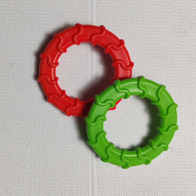 May include: Two plastic rings, one red and one green, with a wavy design. The rings are interlocked.