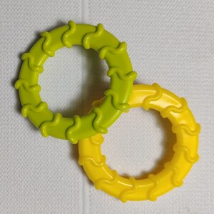 May include: Two interlocking plastic rings, one green and one yellow, with a wavy pattern.