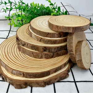 Pode incluir: Um conjunto de seis fatias redondas de madeira, cada uma com um diâmetro diferente, empilhadas umas sobre as outras. As fatias são de madeira castanho claro com padrões de grão visíveis.