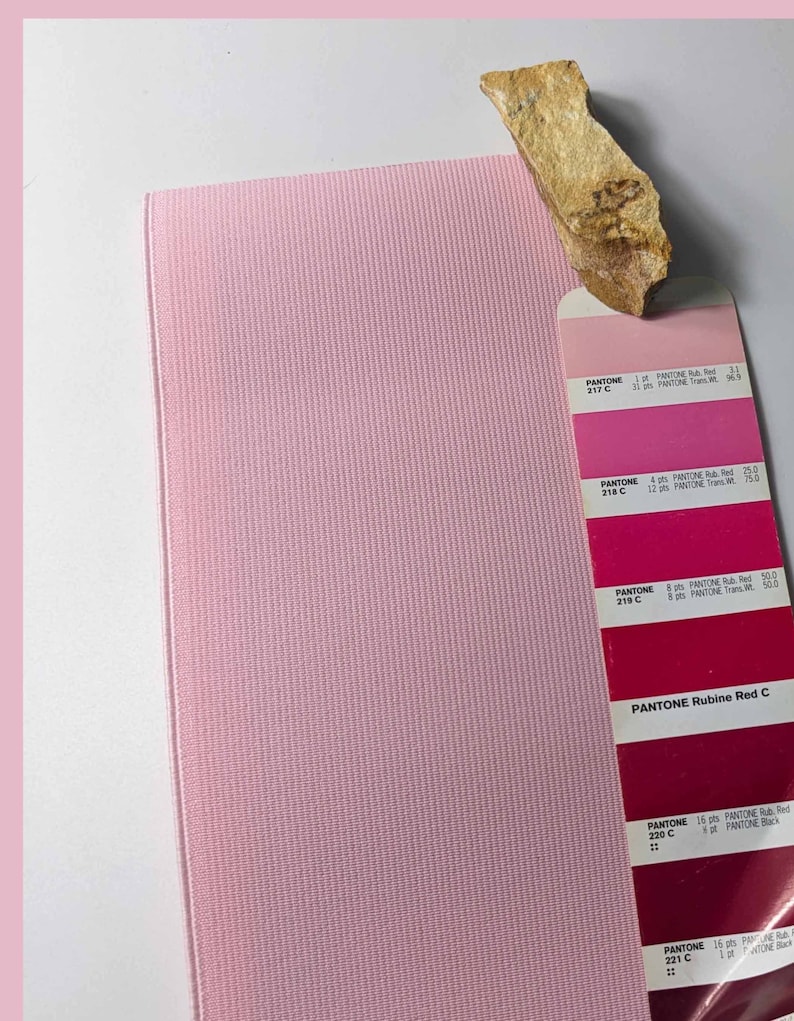 Peut inclure: Un &eacute;chantillon de tissu rose &agrave; c&ocirc;t&eacute; d'un nuancier avec diff&eacute;rentes nuances de rouge. Le nuancier est intitul&eacute; "PANTONE Rubine Red C".