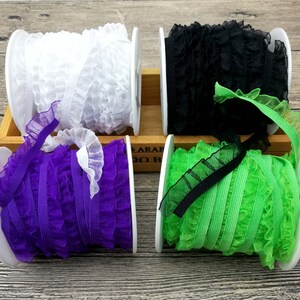 May include: Four spools of ruffled elastic trim in white, black, purple, and green.
