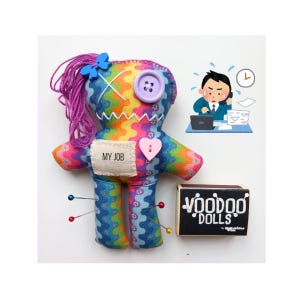 May include: A handmade voodoo doll with rainbow fabric, purple yarn hair, and a blue bow. The doll has a heart-shaped patch and the text "MY JOB". A small box labeled "voodoo dolls" is next to the doll.