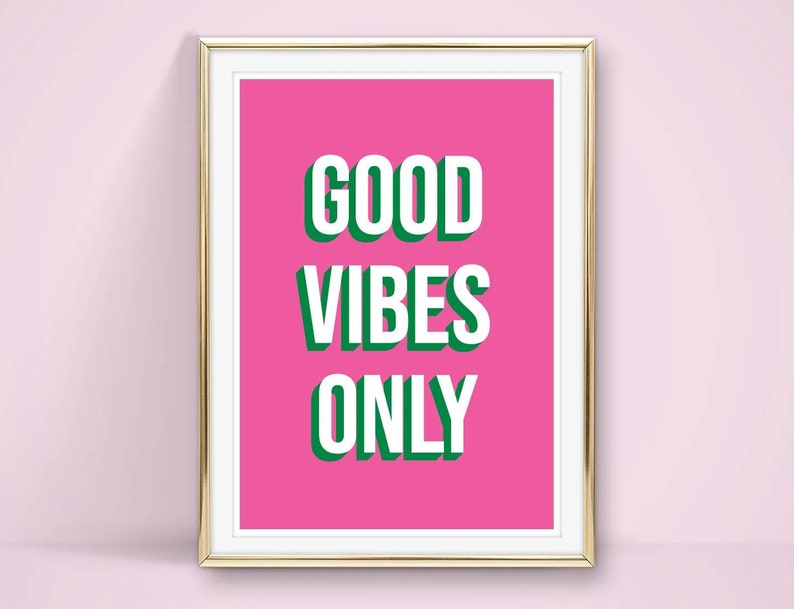 May include: A framed pink poster with the text "GOOD VIBES ONLY" in white letters with a green outline.