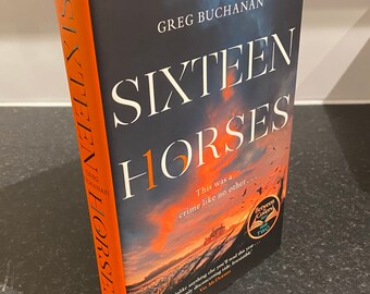 Puede incluir: Un libro de tapa dura titulado "SIXTEEN HORSES" de Greg Buchanan. La portada presenta una dramática escena de puesta de sol con un cielo oscuro y un campo. El lomo es naranja con el título impreso verticalmente.
