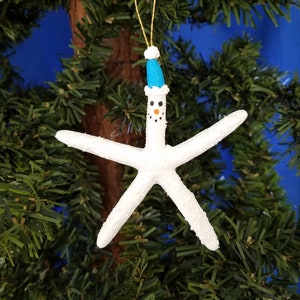 Handmade Starfish Snowman Christmas Ornament. White pencil starfish are painted with textured paint to look like snow. They have a blue hat trimmed in white and a gold hanger. They make great package and gift decorations or Christmas party favors.