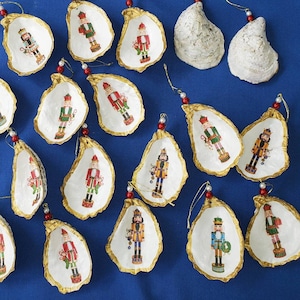 May include: A collection of 15 oyster shell ornaments, each featuring a different nutcracker design. The ornaments are decorated with colorful details and are ready to hang on a Christmas tree.